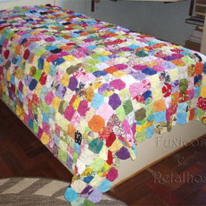 Colcha de Fuxico Solteiro Queen colorida exposta sobre uma cama de solteiro
